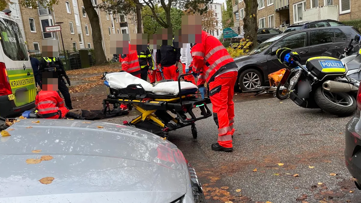 Rettungskräfte und eine Trage in der Conventstraße; ein Polizeimotorrad liegt auf der Fahrbahn auf der Seite.